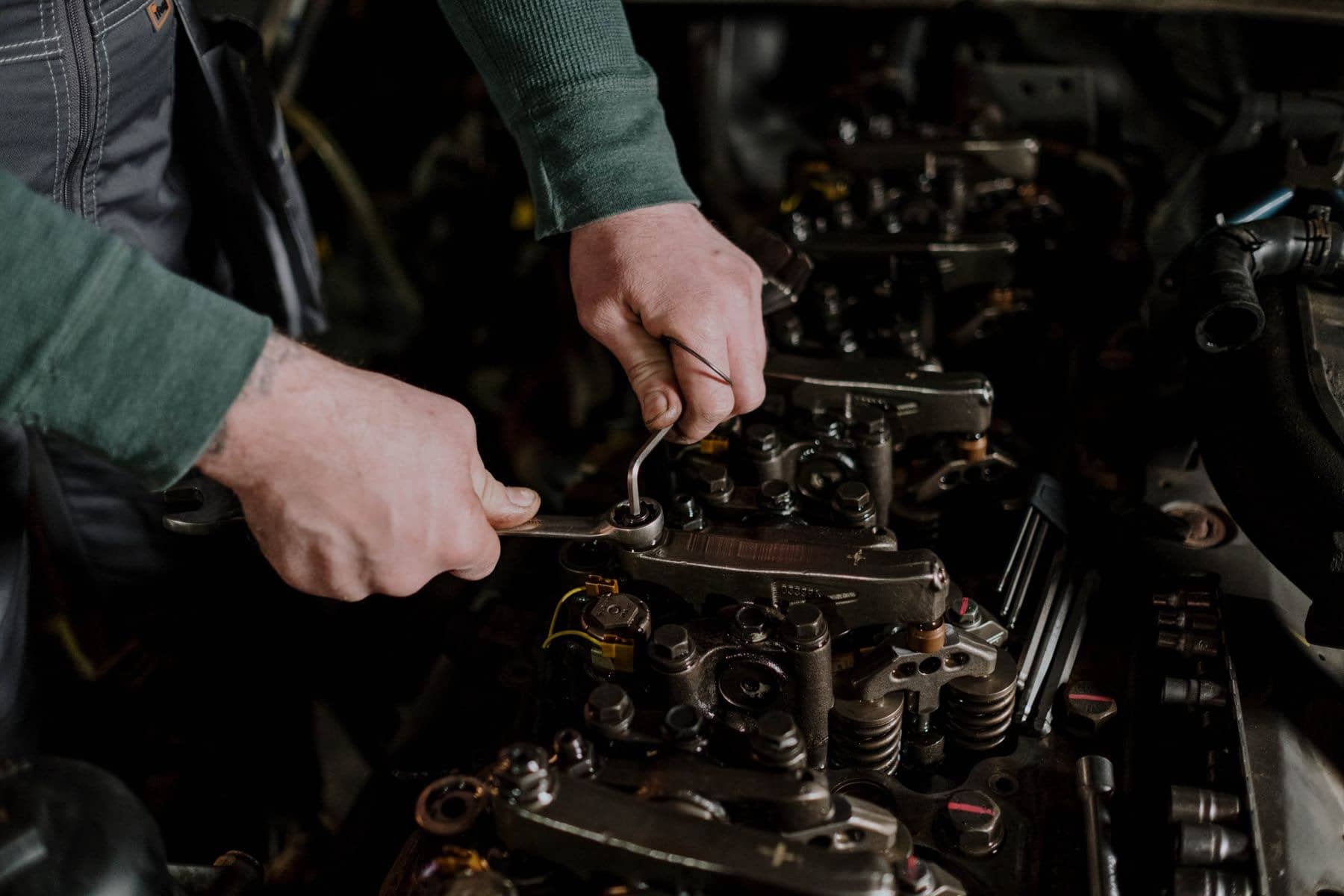 Mechanic's hands turning a ratchet on an exposed engine valvetrain