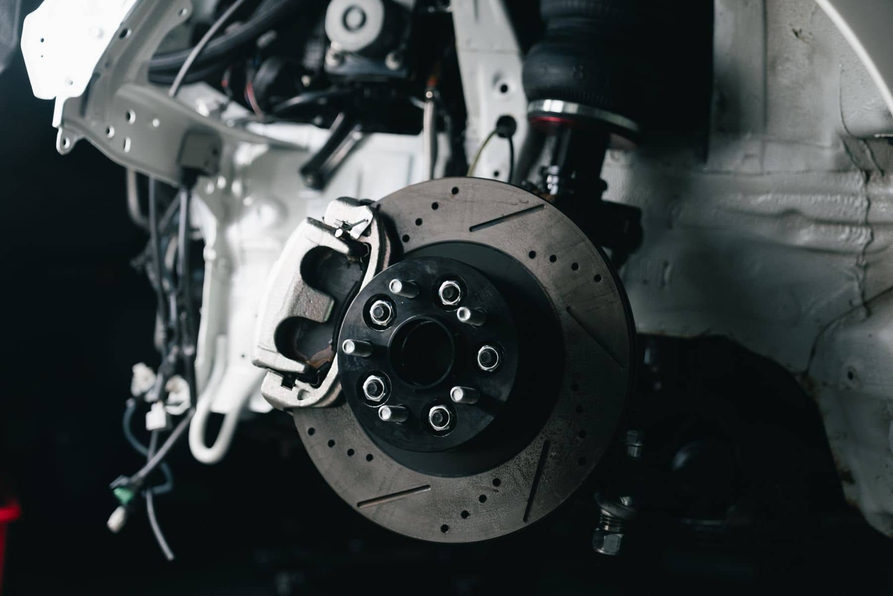 Disc brake caliper and rotor with the wheel removed, in low light