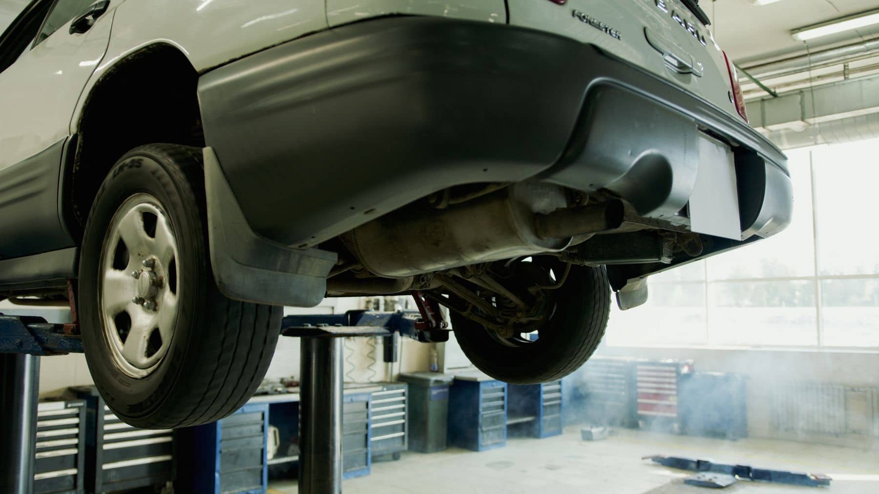 Underside of an SUV raised on a two-post lift in a service bay
