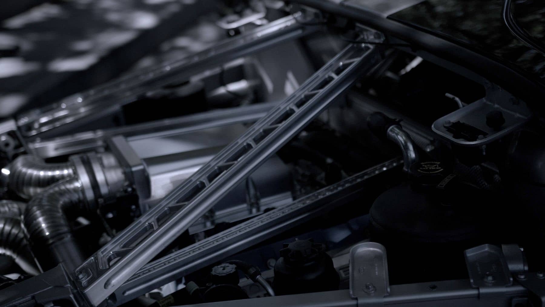 Engine bay with a strut brace and intake plumbing in dim light