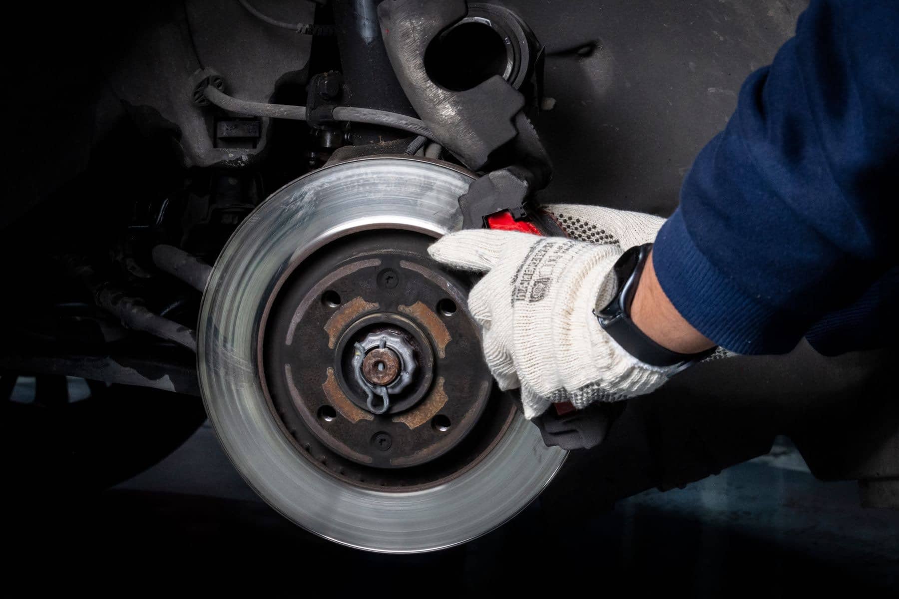 Gloved hand fitting a brake rotor onto a wheel hub