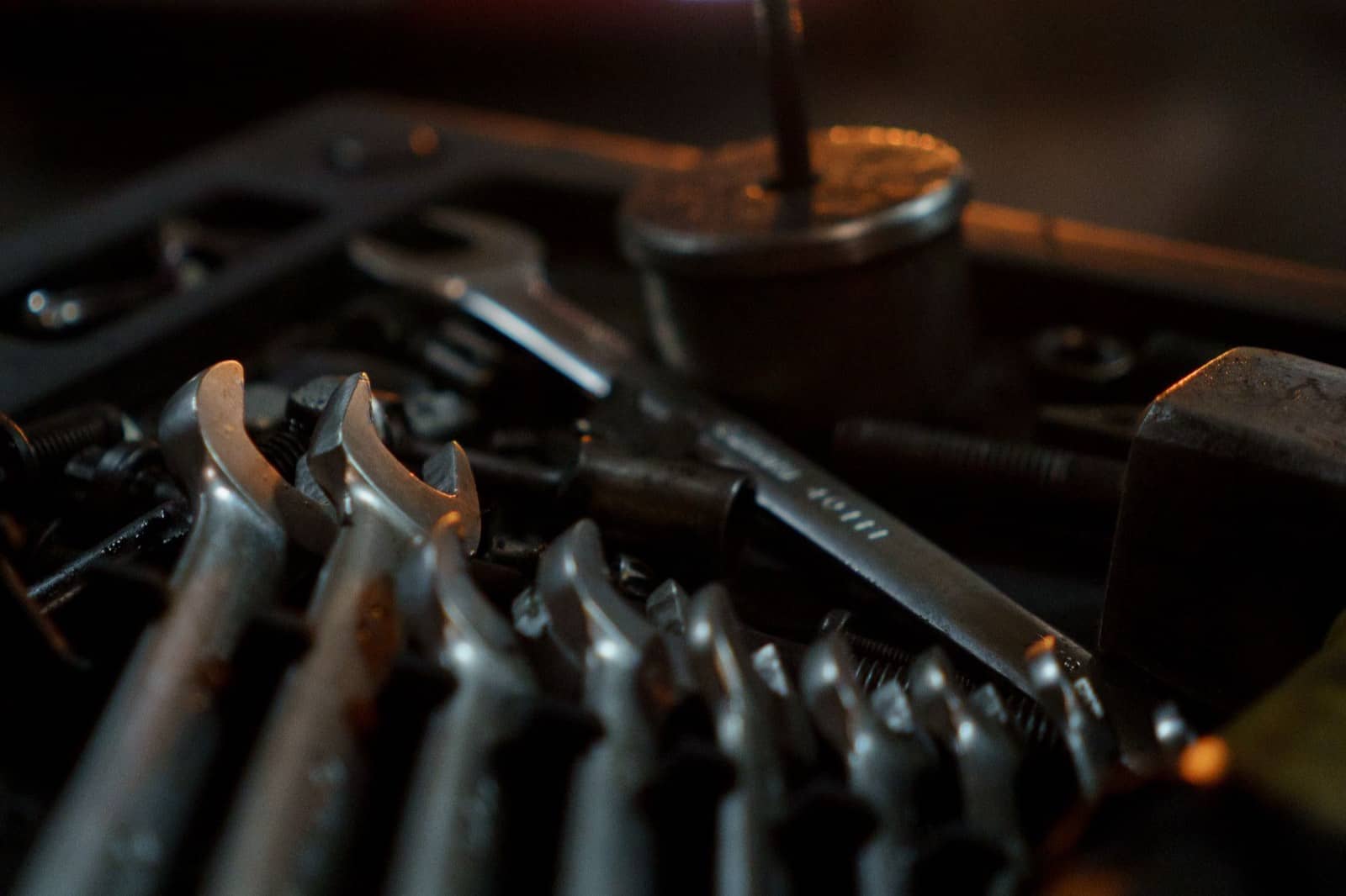 Combination wrenches in a tool tray with a car's lights glowing in the background