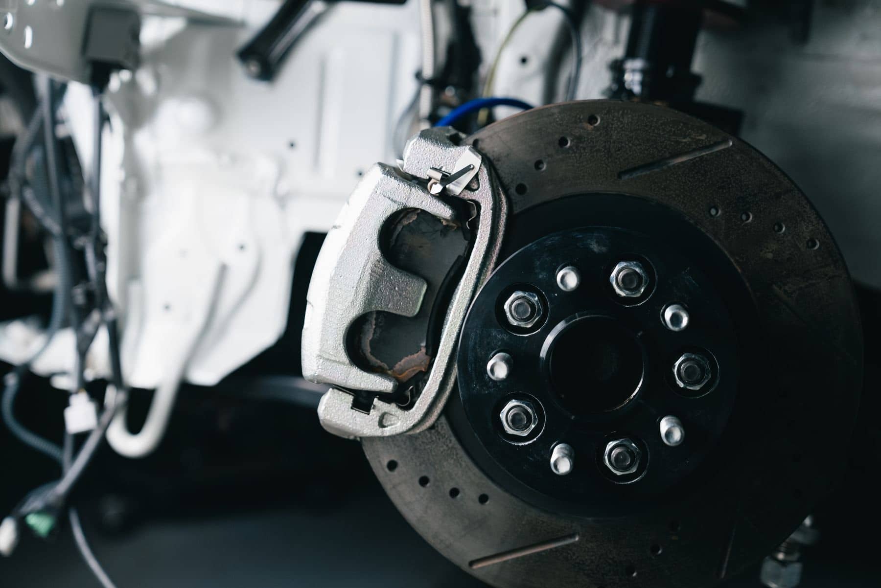 Brake caliper and disc on a hub with the wheel removed, in a dark workshop